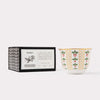 AKUN Scents of Arabia amber candle captured in a calm studio still life with patterned ceramic cup and box