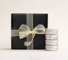 AKUN Scents of Arabia discovery candles arranged beside a ribbon-wrapped black box, highlighting the tin collection format